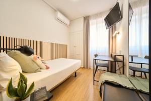 a room with a bed and a table and a television at Hotel Centro Vitoria AutoCheckIn in Vitoria-Gasteiz