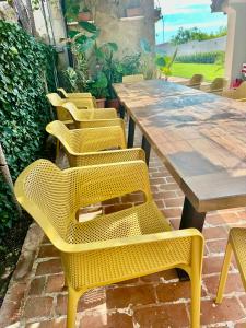 a row of yellow chairs and a wooden table at Къщата в Ахелой in Aheloy