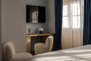 a bedroom with a desk and two chairs and a bed at Hotel des Quinconces Bordeaux Centre in Bordeaux