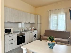 a kitchen with white cabinets and a table and a couch at Villa Silla - Casa Vacanze in Delia