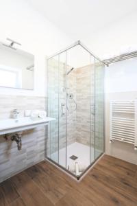 a glass shower in a bathroom with a sink at Leukos Home Relais Ecoretreat b&b in Diamante