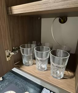 four empty glasses sitting on a shelf in a cabinet at Modern and fully equipped studios in Bosque, downtown area in Rio Branco