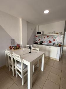 a kitchen with a white table with chairs and a bottle of wine at Apartamentos La Posta in San Salvador de Jujuy