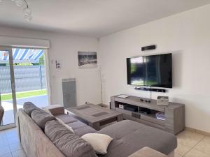 a living room with a couch and a flat screen tv at Avec piscine à Dolus in Dolus-d'Oléron