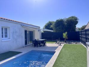 a backyard with a pool and a table and chairs at Avec piscine à Dolus in Dolus-d'Oléron