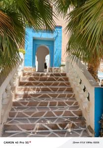 a staircase leading to a blue building with palm trees at Riad tinghir in Tinerhir
