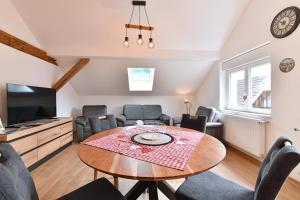 a living room with a table and chairs and a tv at Printemps et Eté en Alsace in Stosswihr