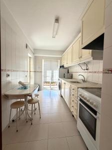 a kitchen with white cabinets and a table and chairs at Casa Caravela B in Armação de Pêra