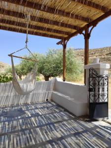 a hammock hanging from a pergola on a patio at Liodentro House in Karpathos