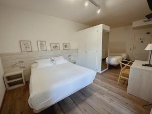 a bedroom with a large white bed and a desk at Hostal Bertran in Salás de Pallás