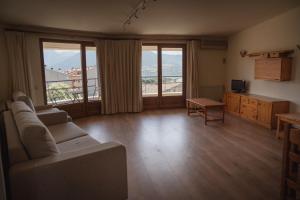 a living room with a couch and a table and windows at Hostal Bertran in Salás de Pallás