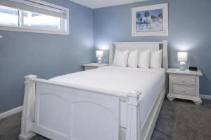 a blue bedroom with a white bed and two night stands at Sugar Beach 353 in Gulf Shores
