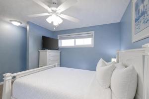 a blue bedroom with a white bed and a ceiling fan at Sugar Beach 353 in Gulf Shores +31 photos