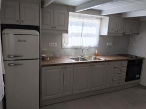 a kitchen with a white refrigerator and a sink at Liodentro House in Karpathos +10 photos