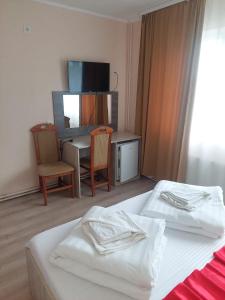 a bedroom with two beds and a desk and a television at Motel Biamin in Tăşnad