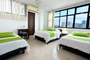 a bedroom with two beds and a desk and windows at Hotel Castell - Cerca Del Aeropuerto in Guayaquil +74 photos