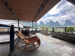 a chair sitting on a patio with mountains in the background at Yangshuo Shui Mo Ju courtyard-Yangshuo Raiway St'ation free pick up for two nights in Yangshuo