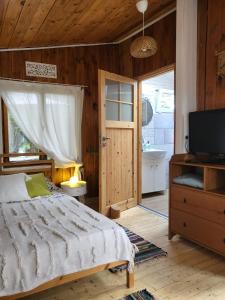 a bedroom with a bed and a television and a bathroom at Retro domki nad Wkrą in Kosewko