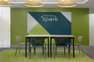 a table with chairs and a wall with a spark sign at Spark by Hilton Edmundston in Edmundston