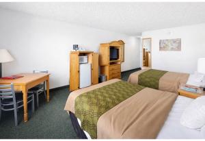 a hotel room with two beds and a desk at Studio 6 Suites Rawlins WY in Rawlins