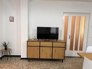 a living room with a flat screen tv on a wooden dresser at Sunflower Apartment in Dogna