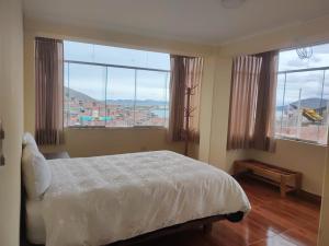 a bedroom with a bed and two large windows at Hospedaje wisny in in Puno