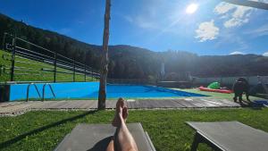 a person laying on a bench near a swimming pool at Manötscherhof in Tires