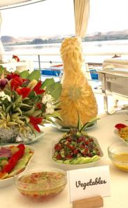 a table with plates of food and a pineapple on it at Dahabiya cruise in Luxor +25 photos