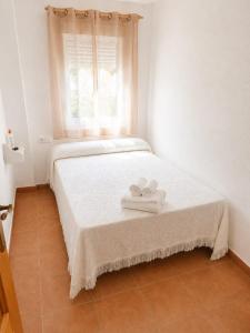 a white bedroom with two towels on a bed at Apartamento Chicago in Mazagón