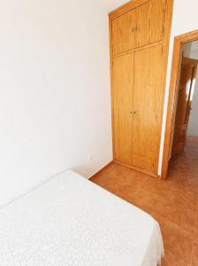 a bedroom with a bed and a wooden cabinet at Apartamento Chicago in Mazagón +4 photos