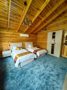 two beds in a room with wooden walls at اكواخ لاكجري ابها in Abha +9 photos