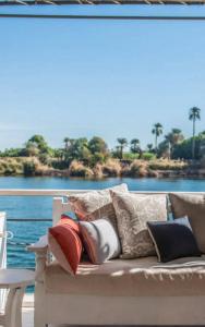 a couch with pillows on a balcony with a view of the water at Dahabiya cruise in Luxor