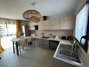 a kitchen with a sink and a table with a counter at Résidence les 3 volcans 4 étoiles in Clermont-Ferrand