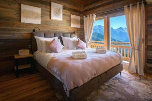 a bedroom with a large bed with a large window at Chalet Serbijanka Alpine Retreat with Hammam Sauna and Jacuzzi for 14 Gueststs in Manigod