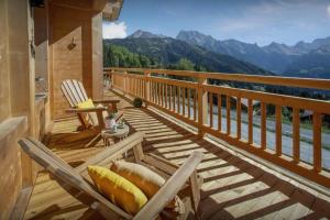 a wooden deck with a table and chairs on a balcony at Chalet Serbijanka Alpine Retreat with Hammam Sauna and Jacuzzi for 14 Gueststs in Manigod