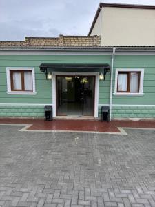 a green building with a door and two chairs in front at Eco Otel in Quba