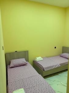 two twin beds in a room with yellow walls at Eco Otel in Quba