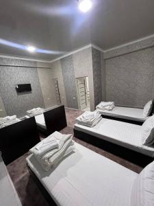 a room with three beds and a tv in it at Sohil Hotel in Stantsiya Kyzyl-Tukumachi