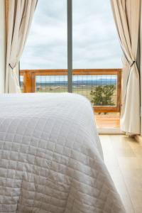a white bed in a room with a large window at Tiny Cabin #3 at The Cedars in Kanab