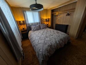a bedroom with a bed with a gray comforter at Cozy Waterfront Cottage in Beaverton