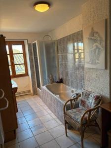a bathroom with a tub and a chair in it at La Parenthèse in Bourg-Saint-Andéol