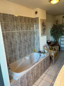 a bath tub in a bathroom with a tile wall at La Parenthèse in Bourg-Saint-Andéol
