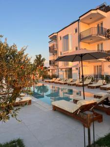a swimming pool with chairs and an umbrella next to a building at Velipoja Residences in Velipojë