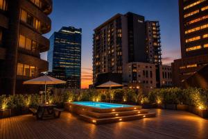 a rooftop patio with a pool in the city at night at One Thibault Hotel - Business Studio in Cape Town