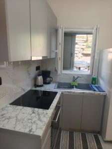 a kitchen with white cabinets and a sink and a window at Agapi's Nest in Agápi +7 photos