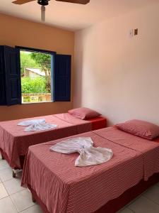 two beds in a room with red sheets and a window at Pousada da Cida in Lençóis