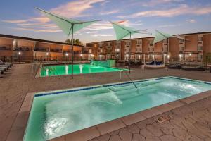 a swimming pool with umbrellas in front of a building at Best Western Denver East in Denver