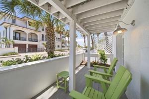 a porch with two green chairs and a balcony with palm trees at Inn on the Beach in St. Pete Beach