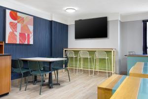 a waiting room with tables and chairs and a flat screen tv at Spark by Hilton Edmundston in Edmundston
