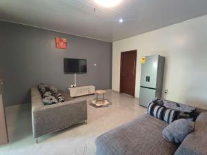 a living room with two couches and a flat screen tv at Lois Beach Resort in Nyanyanu